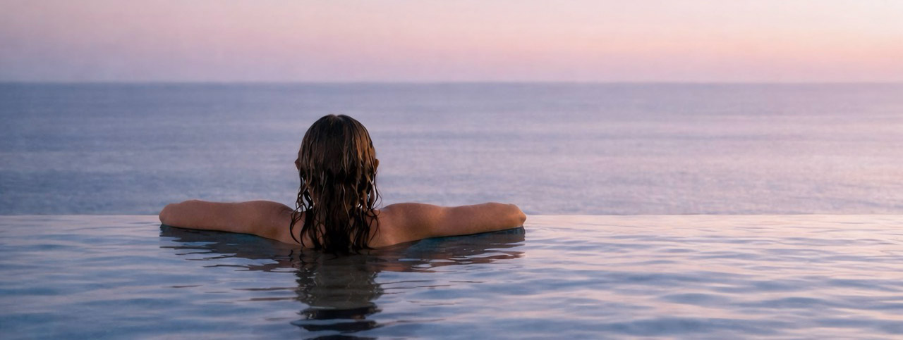 Rooftop infinity pool facing the sea at dusk
